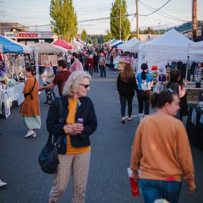 people stroll through the farmers market on a sunny day