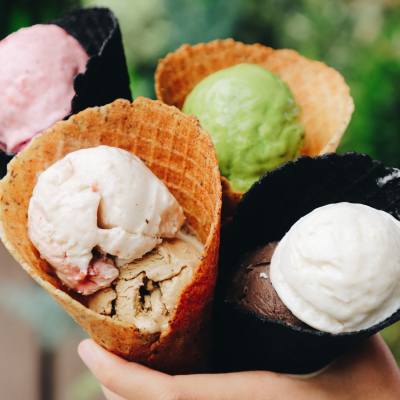 A person holds a variety of ice cream scoops in different waffle cones.