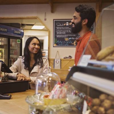 A man and woman smile as they stand behind the counter at a bakery