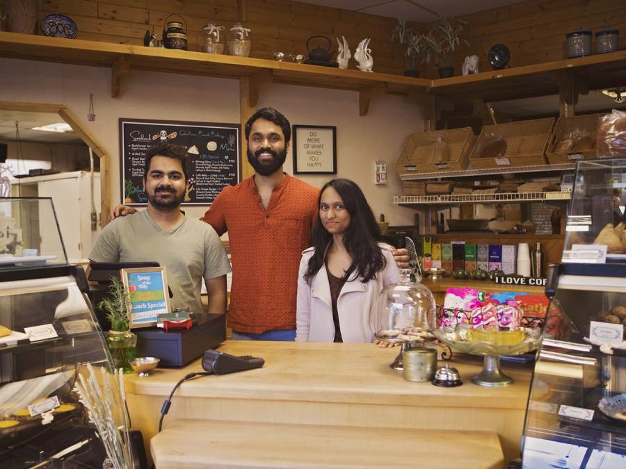 Two men and a woman pose for a photo behind the counter of Qualicum Beach Bakery