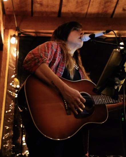 close up of a musician singing and playing acoustic guitar at Rusted Rake