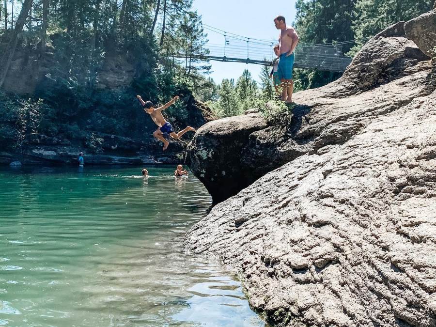 A boy jumping off a rock by the swimming hole at Top Bridge Park.
