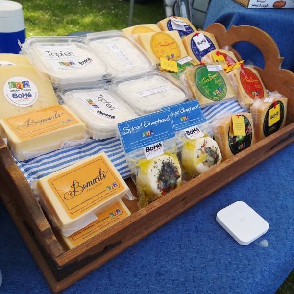 Table display of BoMe Cheeses at a farmers market in Parksville Qualicum Beach, Vancouver Island.