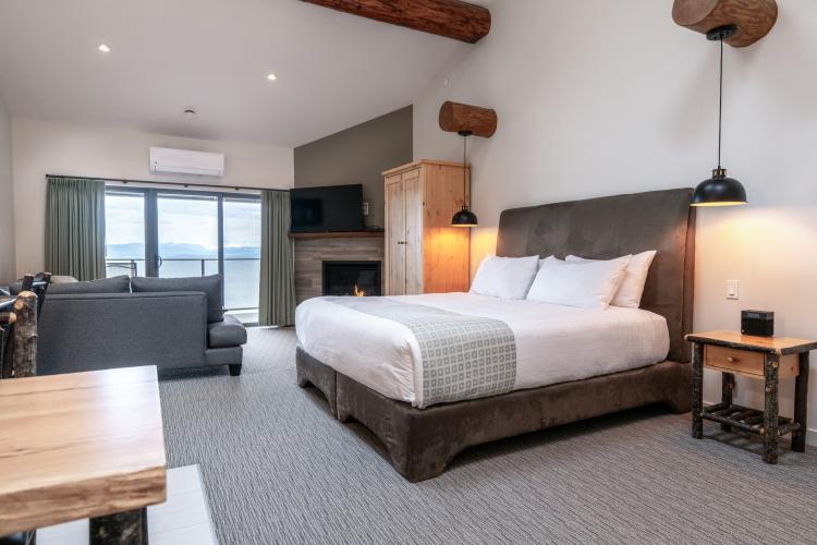 Interior of a room at Tigh-Na-Mara Resort, with tall ceilings, bed, sitting area and doors going out to an ocean view patio.