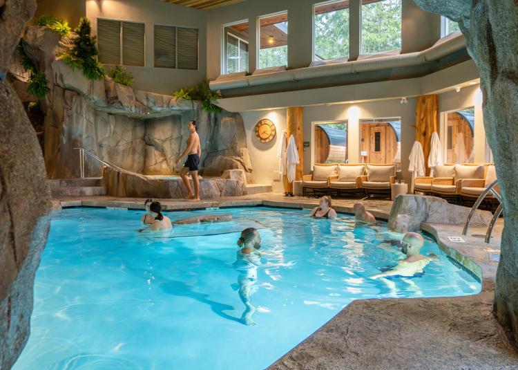 The turquoise waters of the Grotto Spa's mineral pool with 5 guests in the water, relaxing and socializing.