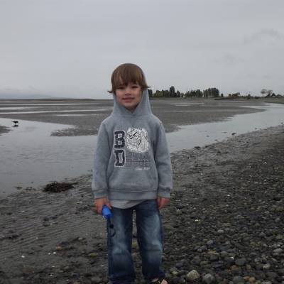 A child beachcombing on Parksville Beach on a gray and rainy day in Parksville Qualicum Beach
