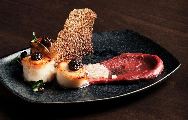 An artistic plating on a black dish of scallops from Treetop Tapas and Grill at Tigh-Na-Mara.