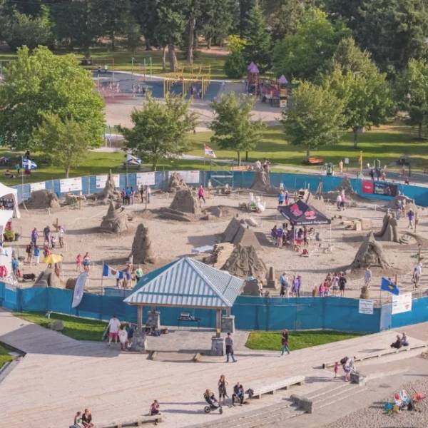 A drone shot of the sand sculpting competition ring with spectators and competitors exploring the artwork.