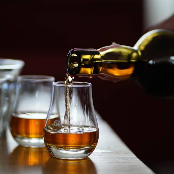 Close-up of a person pouring whisky into two glasses at a distillery near Parksville Qualicum Beach