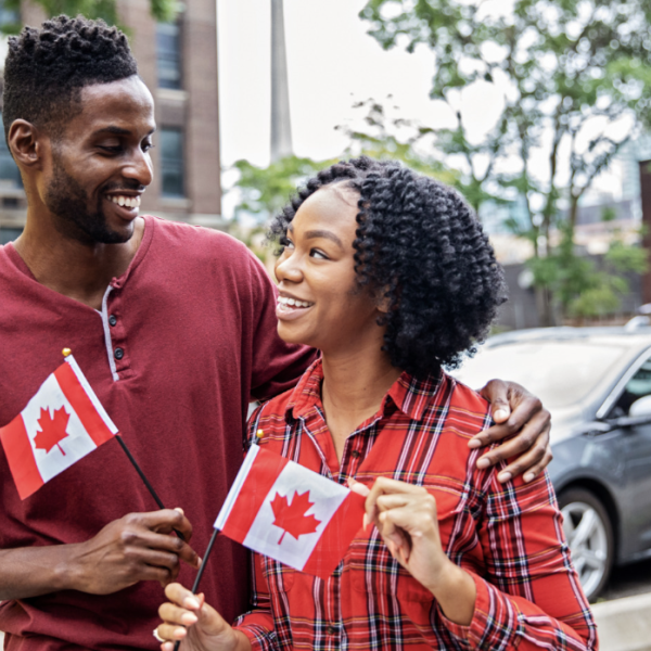 Couple holding small Canadian flags as they walk down the street as sports fans