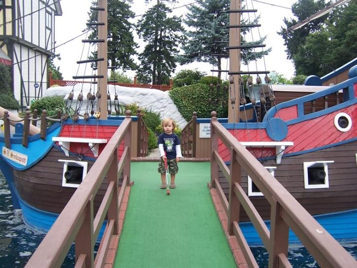 A child stands in a mini golf course at Paradise Mini Golf and Fun Park.
