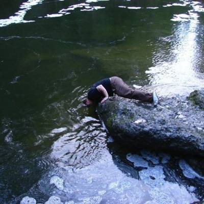 Man leaning in water to catch fish with bare hands in the Englishman river in Parksville, BC