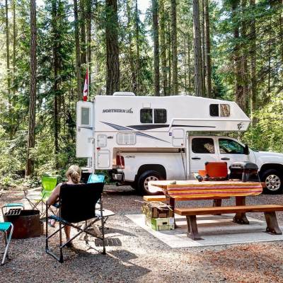 A pickup truck with camper attachment is parked behind a picnic table in Rathtrevor Beach Provincial Park in British Columbia