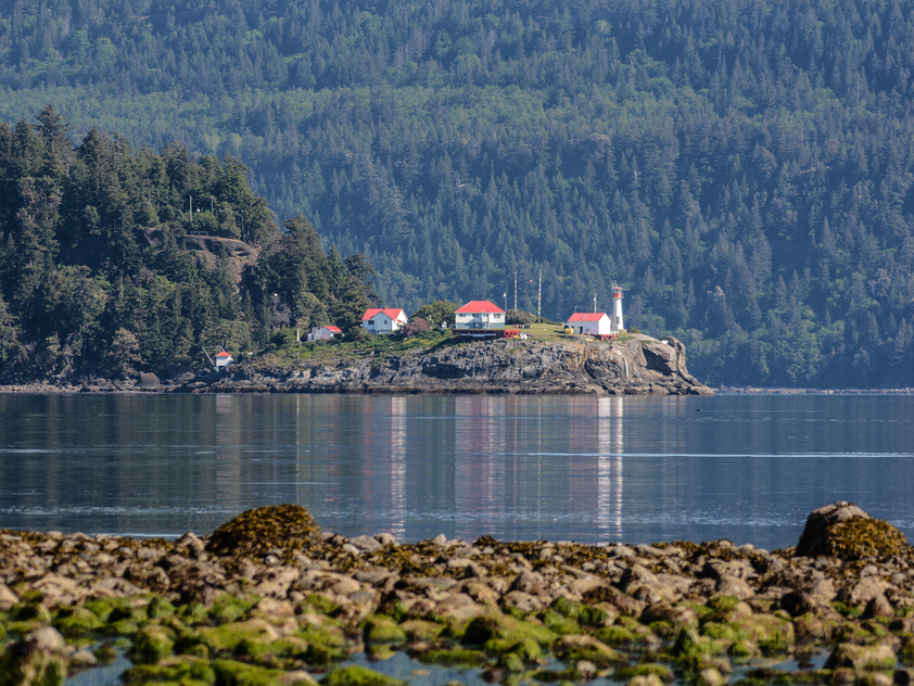 A lighthouse and a few buildings stand across the waters in the distance in Lighthouse Country.