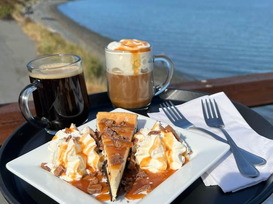 Two cups of coffee and a slice of cheesecake overlooking the shore.