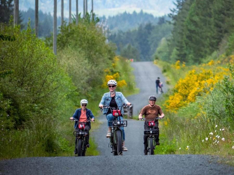 Three cyclists ride bikes along a gravel bike trail in Parksville Qualicum Beach