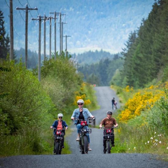 Three cyclists ride bikes along a gravel bike trail in Parksville Qualicum Beach