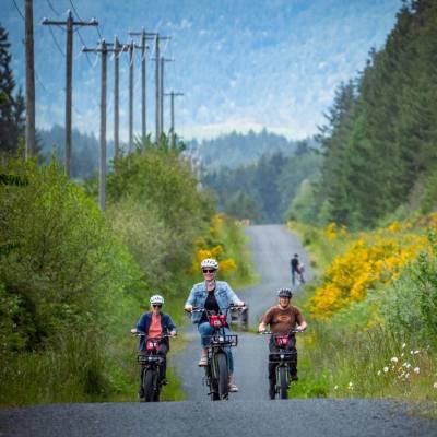 Three cyclists ride bikes along a gravel bike trail in Parksville Qualicum Beach